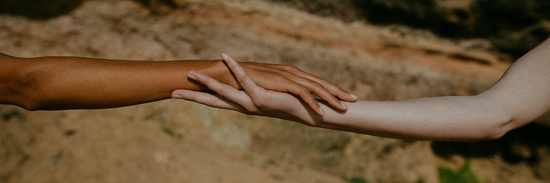 two female arms of different ethnicity stretched out touching each other